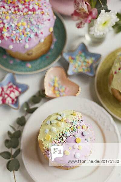 Easter cakes decorated with sprinkles arranged on table