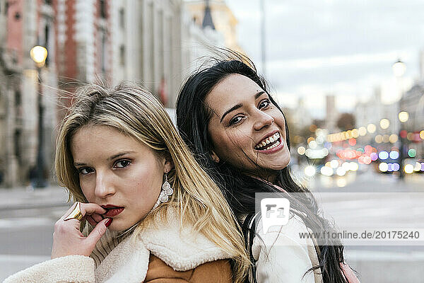 Happy young woman laughing with friend in city