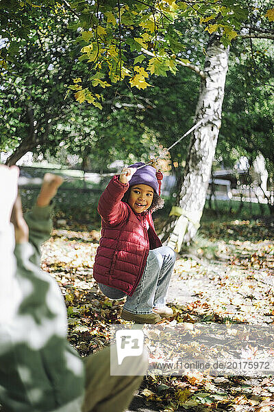 Playful girl hanging on rope while playing at park
