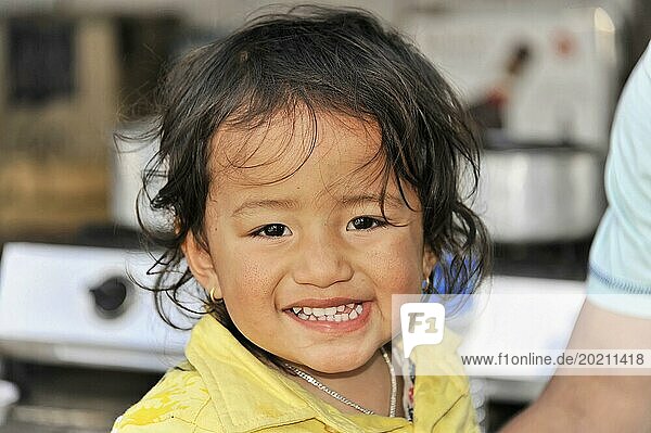 Ein lächelndes Kind in gelber Kleidung strahlt Freude aus  Chitwan Nationalpark  Nepal  Asien