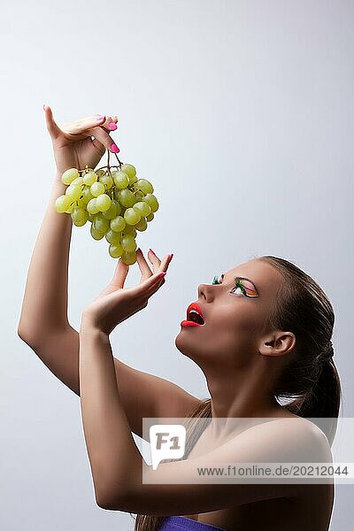 Sexy junge Frau ißt grüne Weintrauben  leuchtet Make up