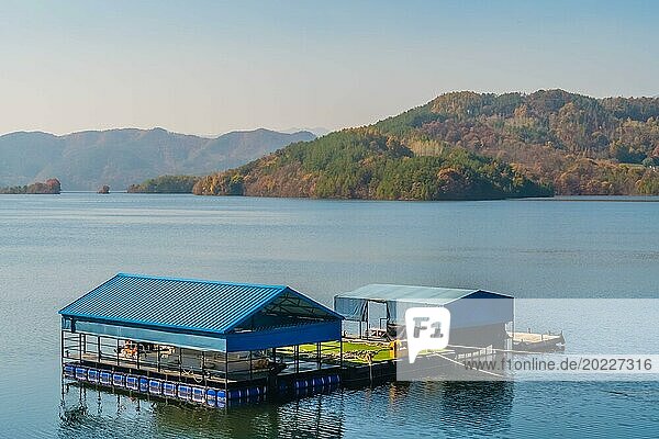 Ein schwimmendes Gebäude mit blauem Dach auf einem ruhigen See mit Bergen in der Ferne  in Südkorea