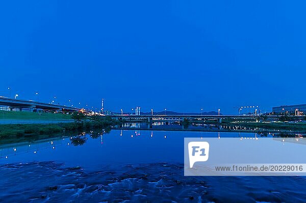 Blaue Stunde Szene von Autobahnbrücken  die sich in ruhigem Wasser mit Stadtlichtern spiegeln  in Südkorea
