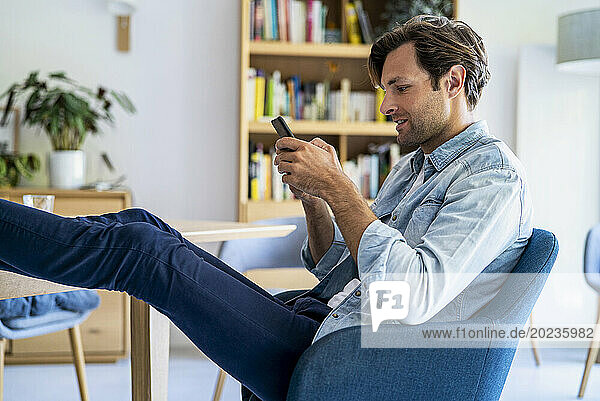 Relaxed businessman working at home sitting on chair with feet on table