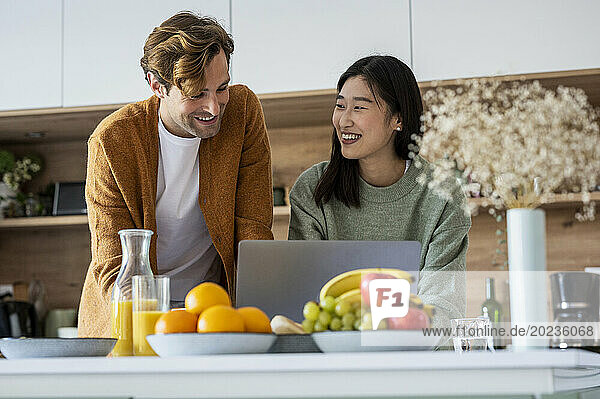 Adult couple using laptop together at kitchen counter