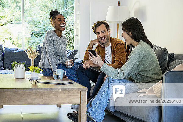 Small group of friends having fun while hanging on living room