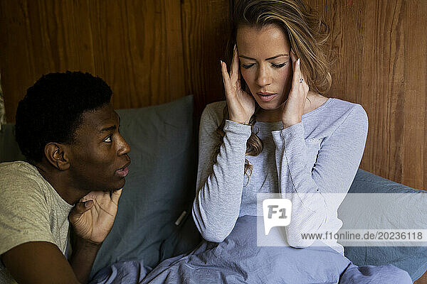 Adult woman having a headache whle talking with boyfriend on bed