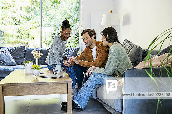 Small group of friends gathered in living room while using smart phone