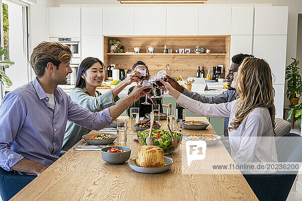 Group of friends toasting with wineglasses during dinner