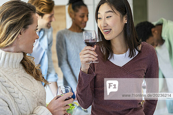 Two friends talking during reunion while drinking wine