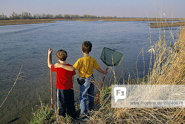 Two young boys with nets prepare to explore a waterway; Gibbon  Nebraska  United States of America