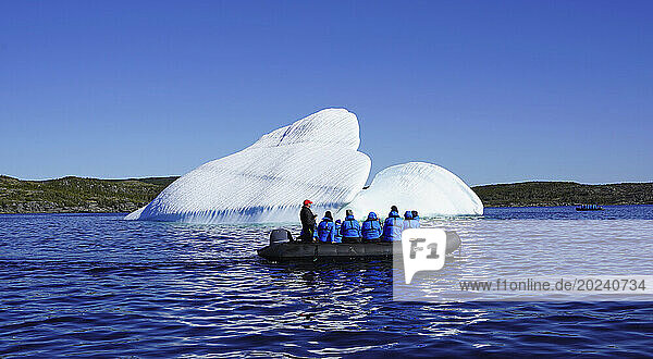 Tourists observing iceberg from inflatable boat