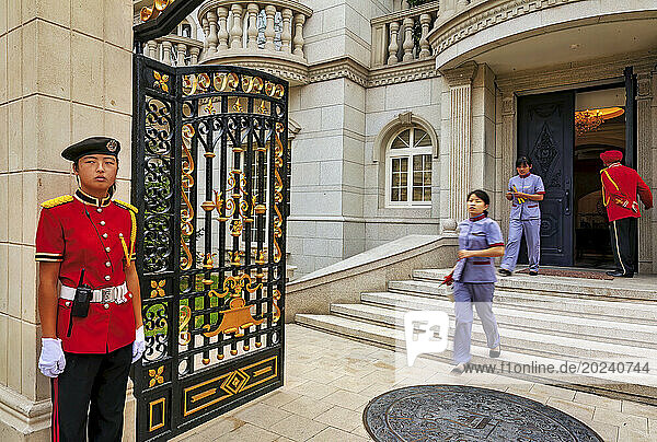 Cleaning staff and guards in red uniform at a villa in the Palais de Fortune development outside Beijing; People's Republic of China