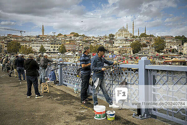 Fishermen at Galata Bridge with Suleymaniye Mosque in the background; Istanbul  Turkey