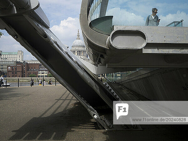 View of St. Paul's Cathedral and the Millennium Bridge from Tate Modern with man looking at mobile phone; London  England