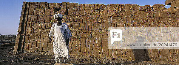 Sudanese man standing next to Egyptian ruins  a Nubian king's tomb from the 25th dynasty. El-Kurru was one of the royal cemeteries used by the Nubian royal family. Egyptian empire began to decay in 1000BC and in 660BC Kingdom of Kush ruled an empire stretching from central Sudan to the borders of Palestine; Sudan