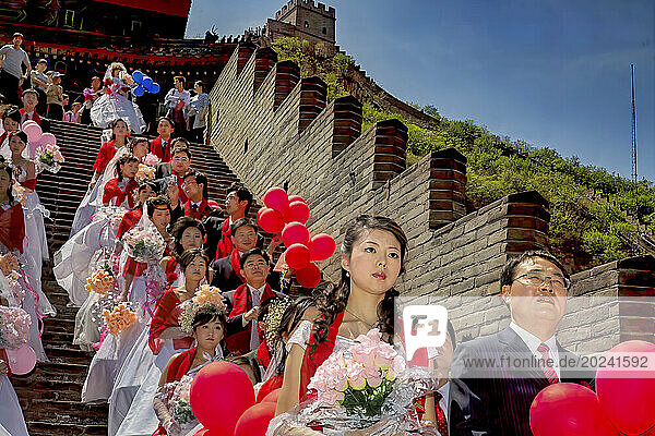 Couples dressed in formal wear stand waiting for the mass wedding that took place at the Great Wall outside Beijing. Some may marry for love  but marriage can also be a great social and financial leap forward; People's Republic of China