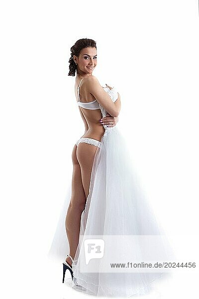 Sexy schlanke Braut posiert in Dessous vor weißem Hintergrund