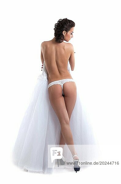 Schlanke nackte Braut posiert mit dem Rücken zur Kamera  vor weißem Hintergrund