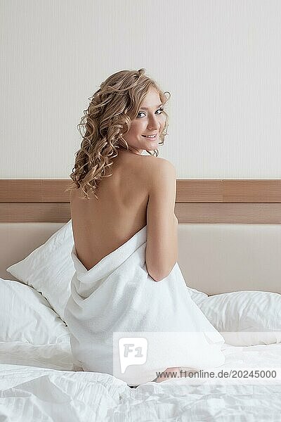 Attraktives junges Mädchen im Handtuch posiert auf dem Bett  Nahaufnahme