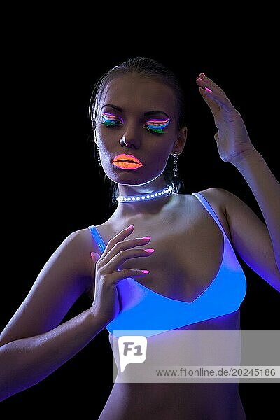 Hübsches schlankes Mädchen tanzt unter fluoreszierendem Licht  vorSchwarz