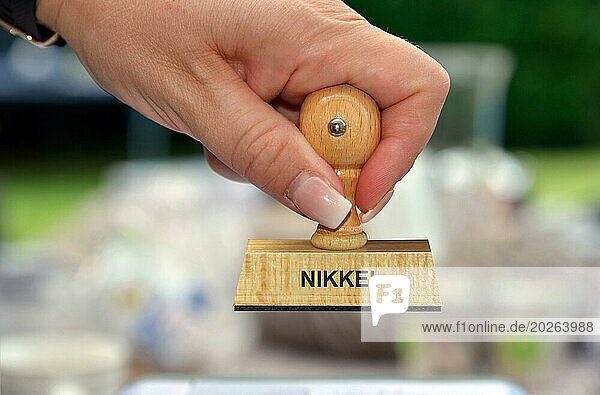 Symbolfoto  Frauenhand mit Stempel  Aufschrift: Stock Market  Nikkei  Studio