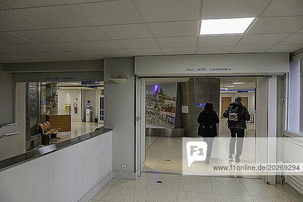 2 people from behind walking in a corridor of the North Hall of a hospital center.