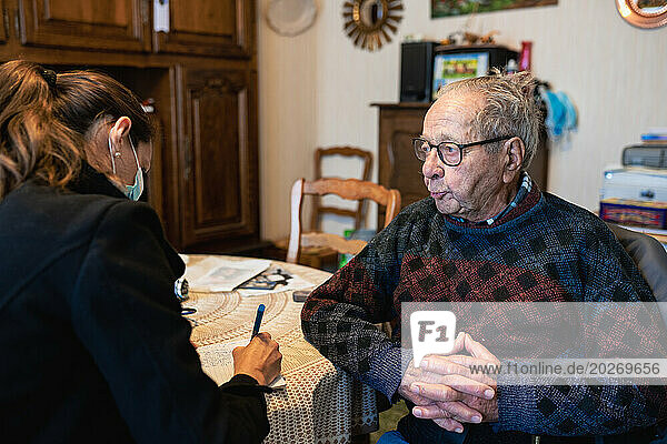 Home care by a nurse who fills out the coordination notebook for a 90-year-old senior and speaks with him.
