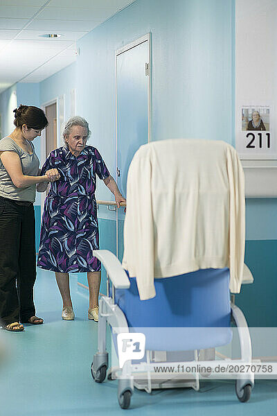 EHPAD - Physiotherapist performing walking exercises with an elderly resident in the hallway.