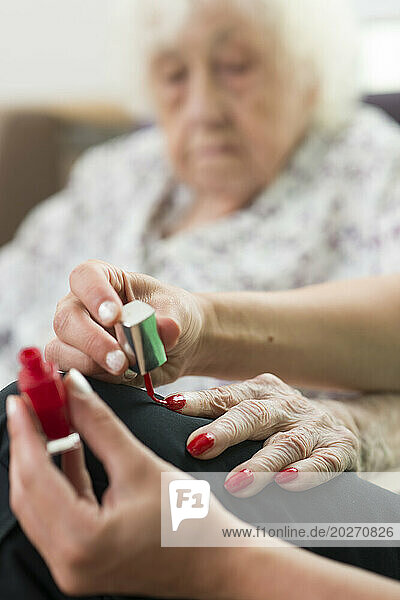EHPAD - A nursing assistant applying nail polish on the hands of an elderly and deaf resident.
