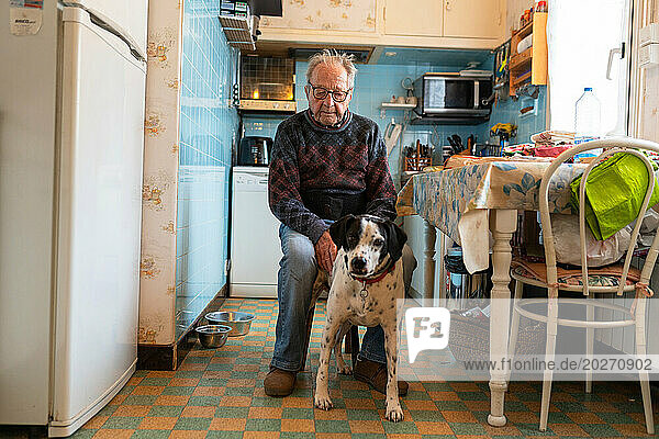 Loneliness of the elderly person  senior living alone with their dog in their kitchen.