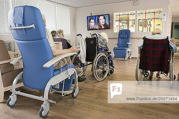EHPAD - Elderly residents in wheelchairs installed in a common room watching television.