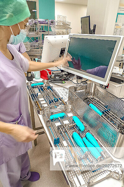 Operator preparing to fill an instrument with the help of the computer for sterilization.
