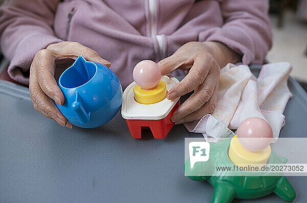 ADMR 62 - Home Help in Rural Areas  Pas de Calais. Veronique  Auxiliary of Social Life (AVS) intervenes in the home of Mr. and Mrs. B.  severely handicapped by Alzheimer's disease. Veronique must help him with all the daily tasks. Dependent elderly person playing with toys for very young children.