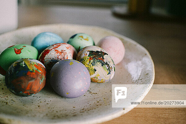 Colorful Easter eggs arranged in plate at home
