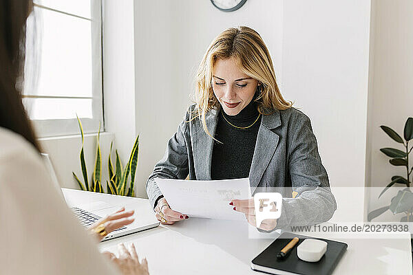 Smiling HR manager reading resume at desk