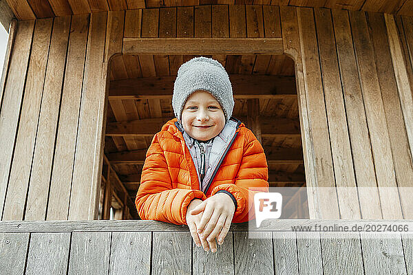 Smiling boy leaning on wooden railing at cabin