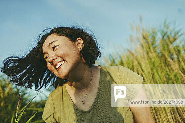 Carefree woman having fun in field on sunny day