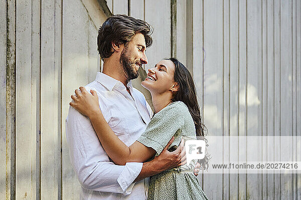 Smiling couple embracing each other in front of wall