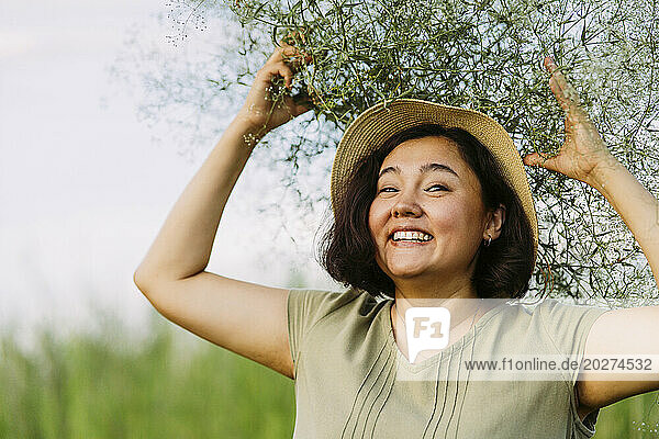 Happy mature woman carrying gypsophila flowers on head in field