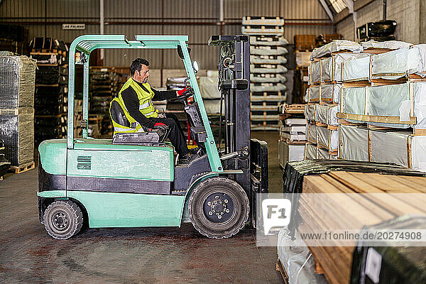 Worker operating forklift at warehouse