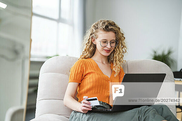 Smiling woman doing payment through credit card at home