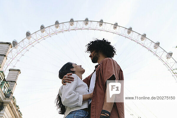 Young couple standing in front of Ferris wheel in London city