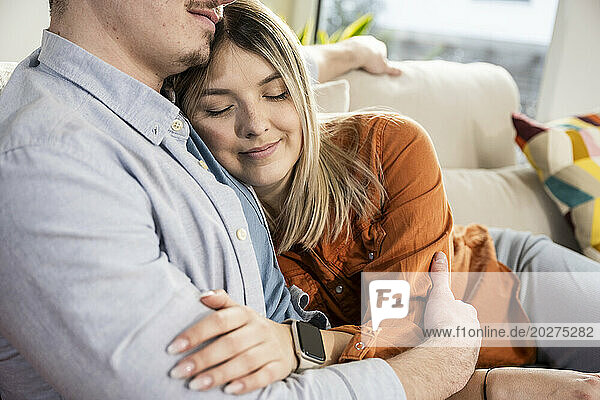 Smiling woman hugging man on sofa at home