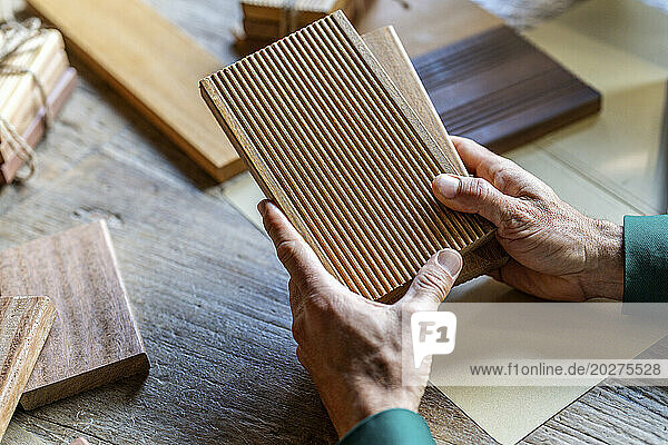 Hands of businessman holding wooden samples in office