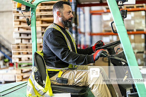 Mature worker driving forklift at warehouse