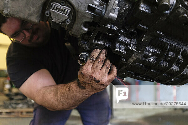 Auto mechanic adjusting parts of engine at workshop
