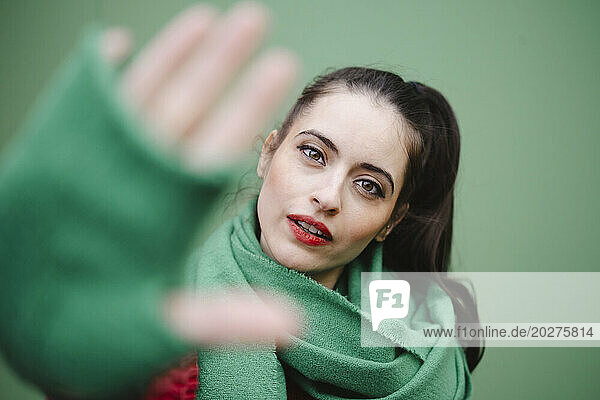 Woman showing stop gesture against green background