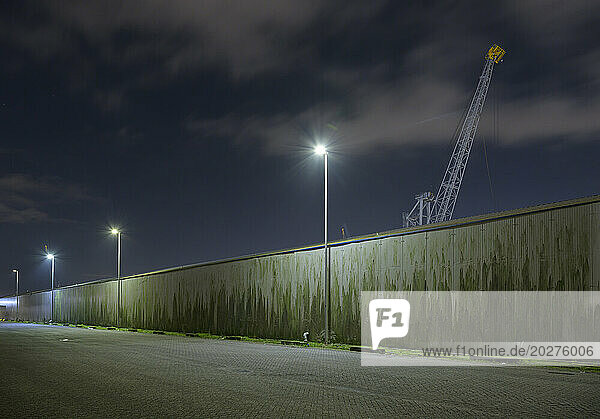 Netherlands  South Holland  Rotterdam  Old harbor cranes seen from behind surrounding wall at night