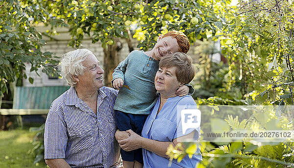 Happy boy having fun with grandparents in garden
